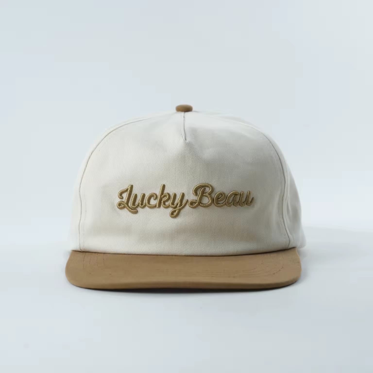 Lucky Beau 5-Panel Cap front, natural cotton crown with camel suede brim and raised gold Lucky Beau script