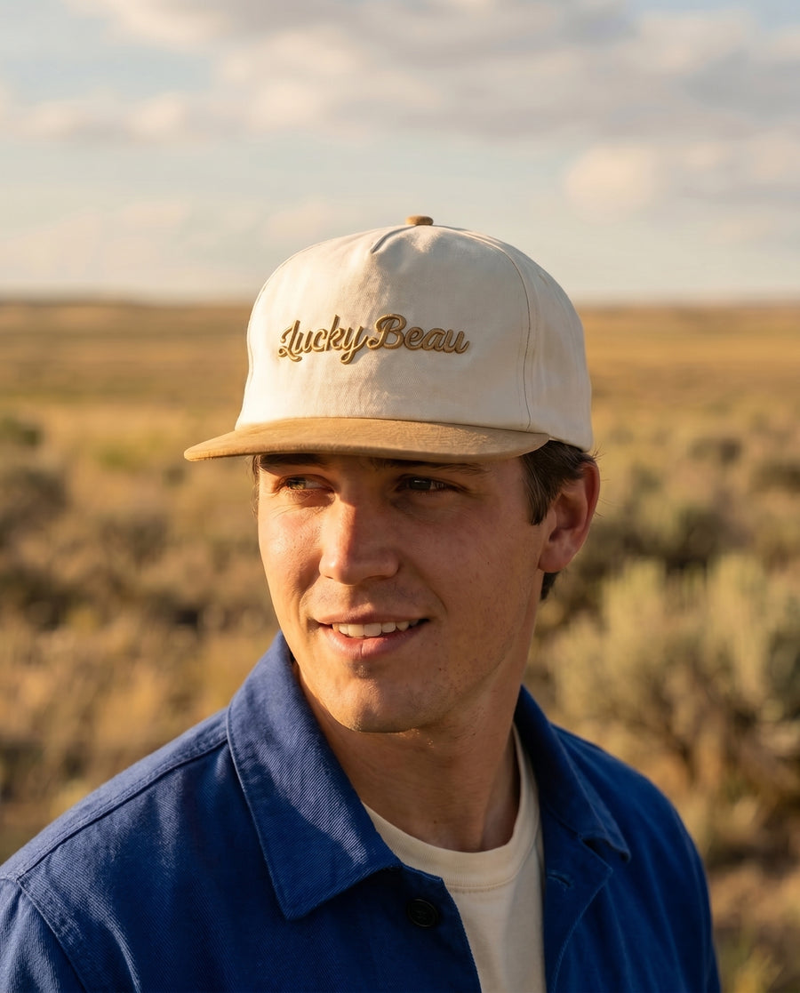 Man in golden-hour high desert wearing the Lucky Beau cap with the Chasseur Bleu jacket