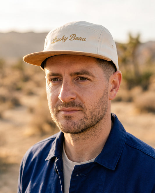 Relatable man in his 40s in golden-hour high desert wearing the Lucky Beau cap with the Chasseur Bleu jacket