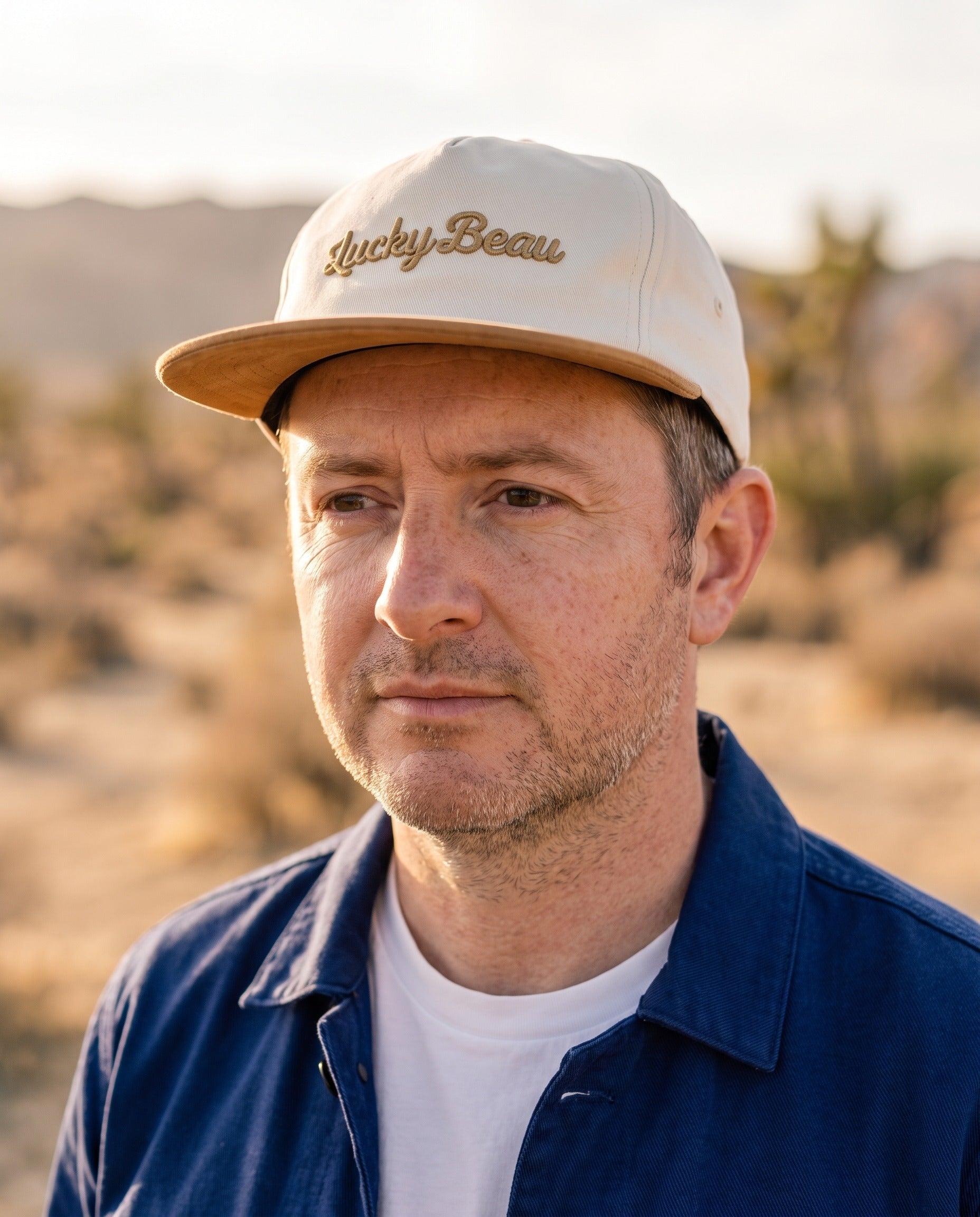 Man wearing the Lucky Beau 5-Panel Cap at golden hour, paired with the Chasseur Bleu jacket
